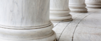 Marble columns stand firmly, lined in a row, on a curved marble walkway, suggesting a classical architectural setting.