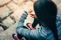 A person in sportswear examines a smartwatch on their wrist, seated on outdoor steps. Digital health data floats nearby: heart rate 127, time 48:10, steps 653.