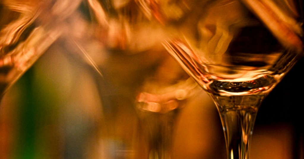 Close-up of glassware bathed in warm amber lighting with a blurred background.